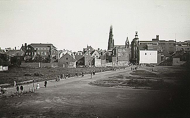 Panorama van de Demer, gezien in de richting van de 'Rechtestraat', met braakliggend terrein als gevolg van het bombardement van 6 december 1942. Op de achtergrond de 'Catharinakerk', het 'Oude Raadhuis' en de 'glazen toren' van 'V&D'. Fotograaf A. van der Heijden.