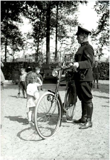 Een politieagent knoopt een gesprekje aan met een jeugdige bezoekster van de speelplaats in het Stadswandelpark in 1939.